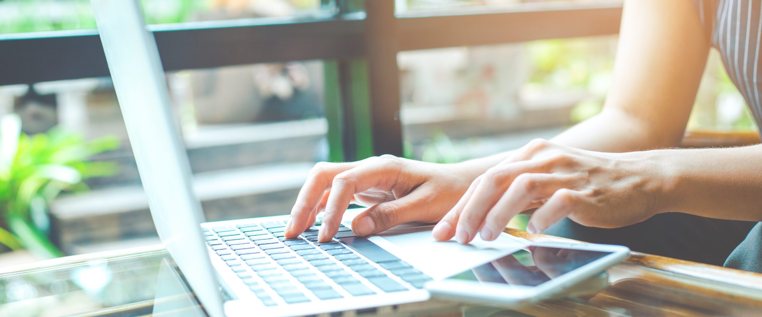 Business woman working with a laptop computer and uses a cell phone in the office.Web banner.